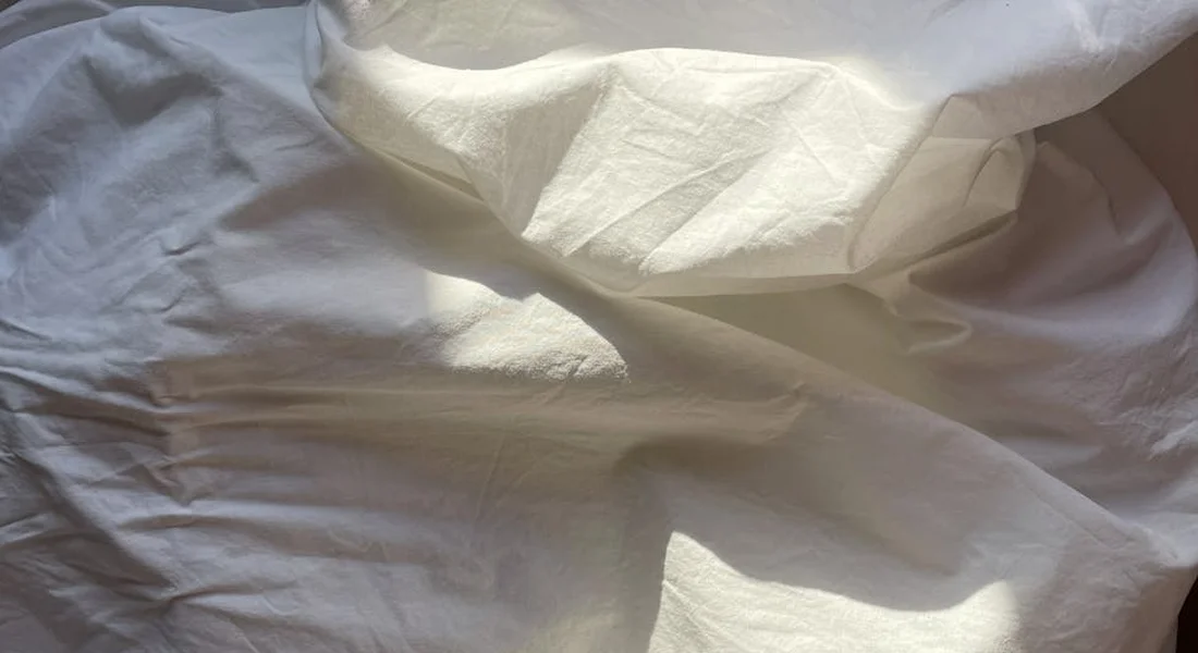 Close-up of white bedding fabric with folds and shadows, representing the bedding materials used in guinea pig cages.