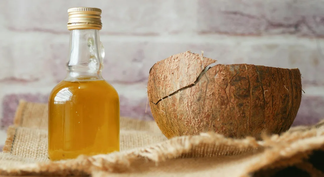 Coconut shell halves and a bottle of coconut oil on a wooden surface, illustrating natural enrichment materials for guinea pigs