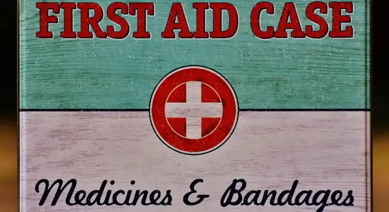 Vintage first aid case sign with a red cross symbol and the words 'FIRST AID CASE' and 'Medicines & Bandages'.