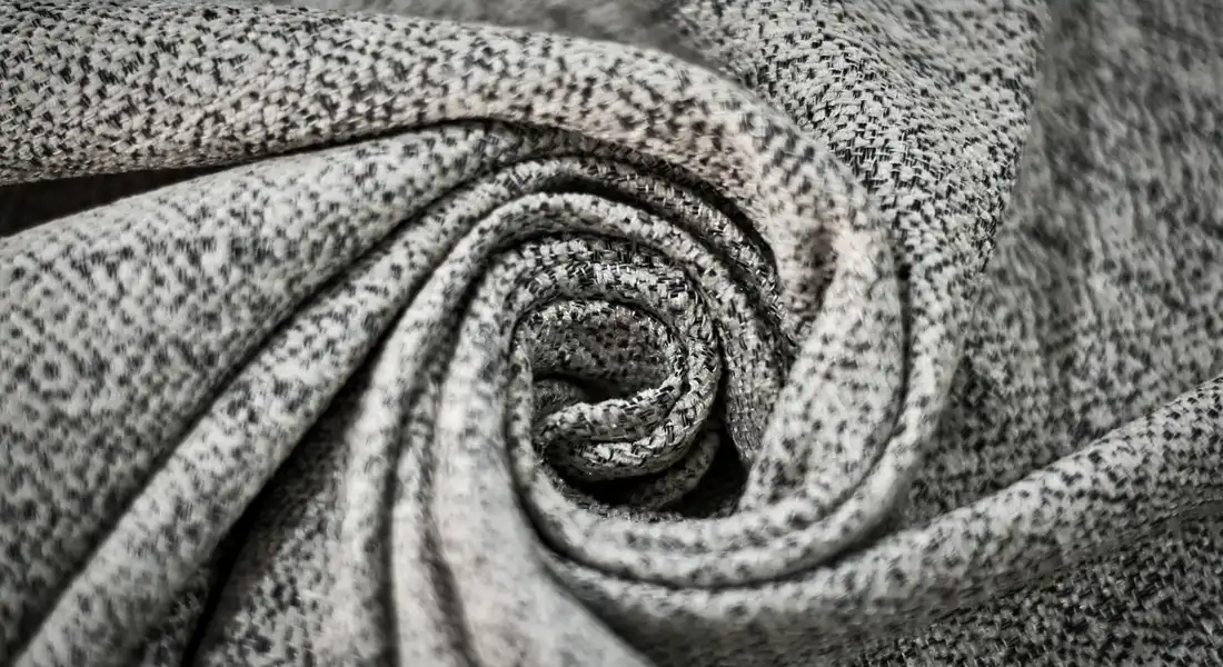 Close-up of speckled gray fleece fabric folded into a spiral.