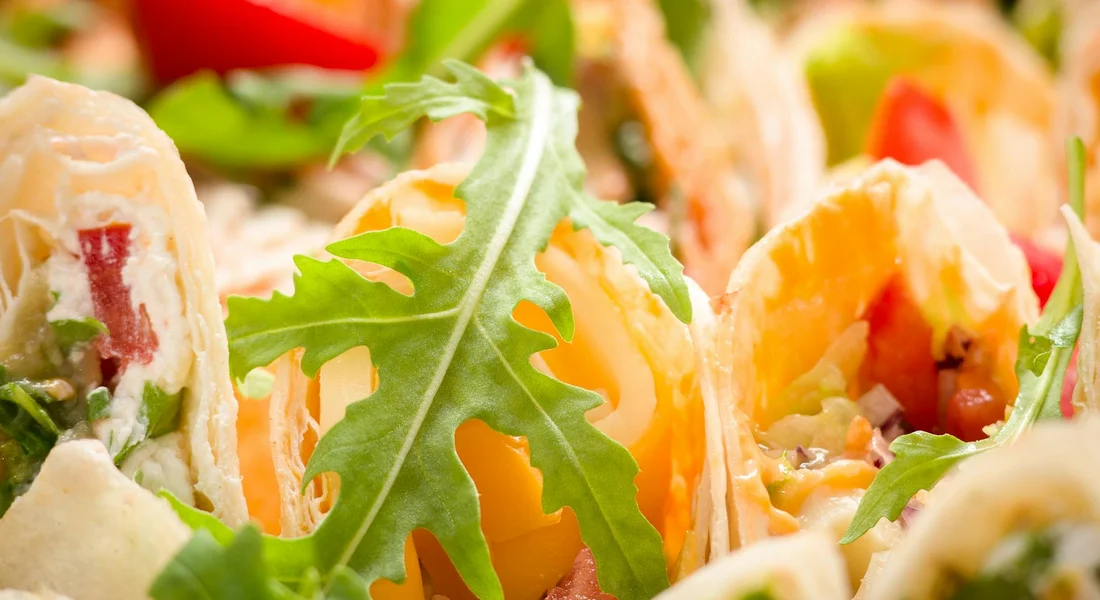 Close-up of fresh greens such as arugula and lettuce on colorful wraps, illustrating foraged greens
