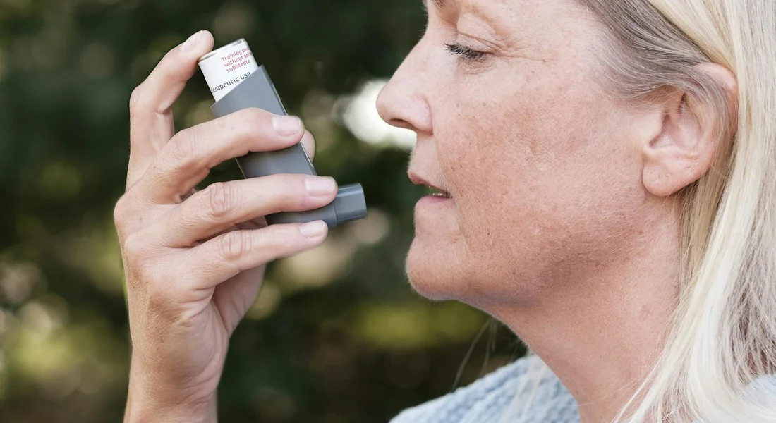 Close-up of a person using an inhaler outdoors, illustrating allergy or asthma management while around guinea pigs.