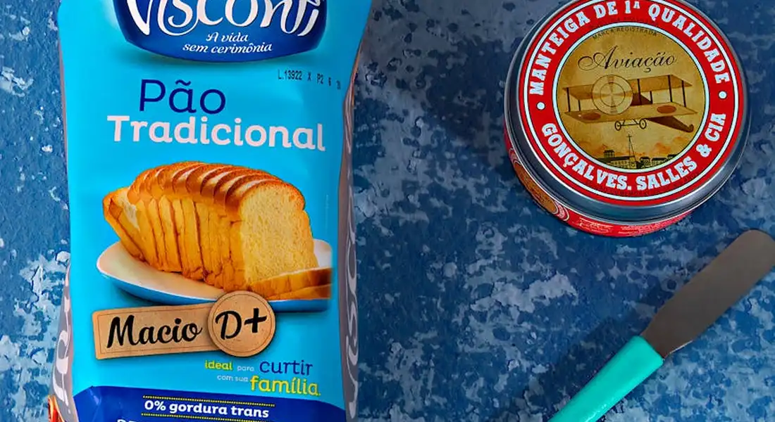 Blue countertop with a loaf bread packaging on the left and a round tin lid on the right, a teal-handled knife nearby.