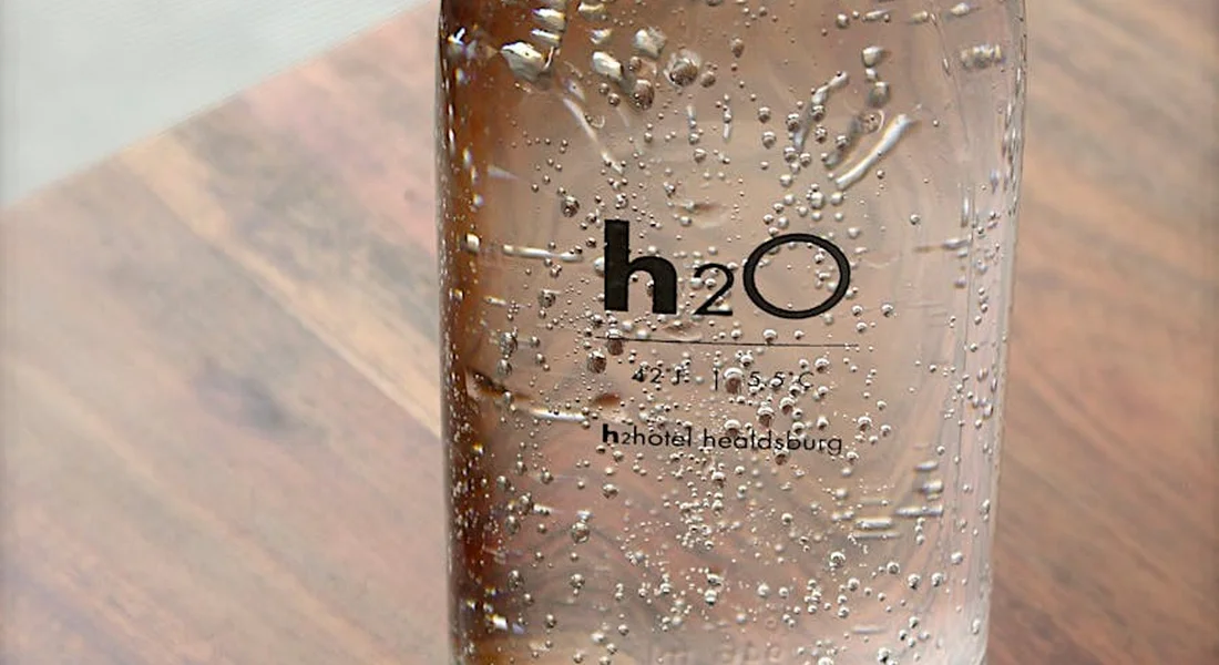 Close-up of a water bottle with droplets on the surface and the label 'h2O' visible.