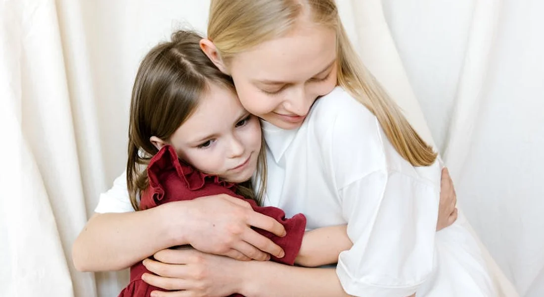 Two young girls share a comforting hug, reflecting the emotional support families seek after a pet's loss.