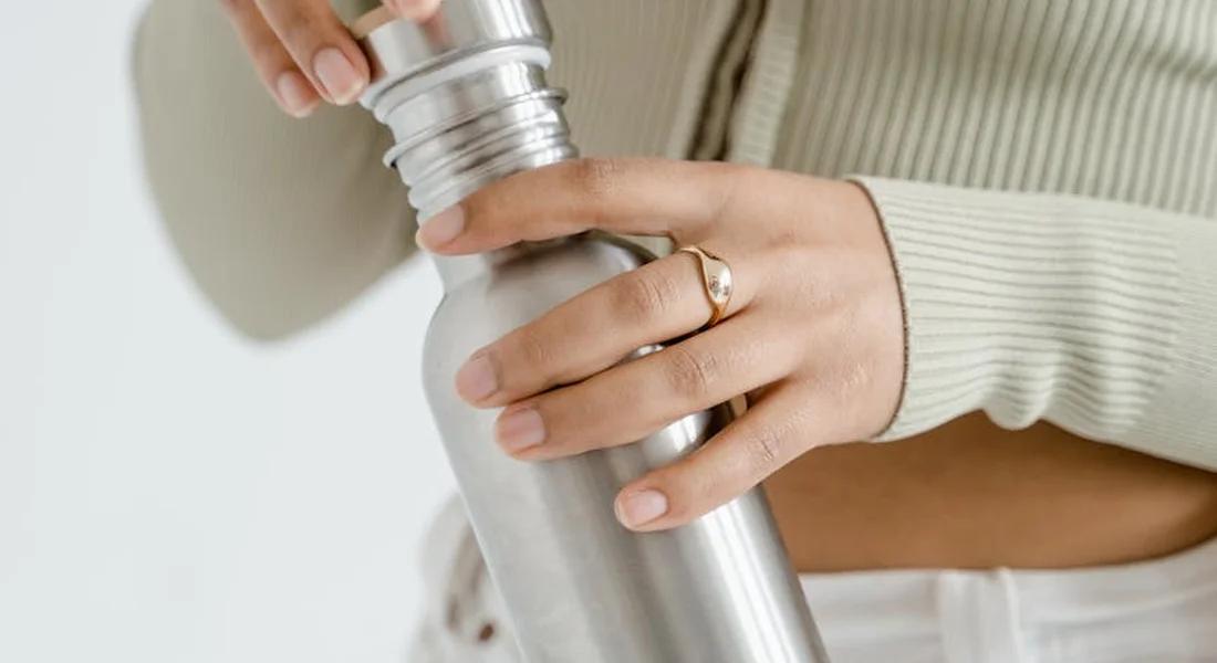Close-up of a person tightening the cap on a stainless steel water bottle