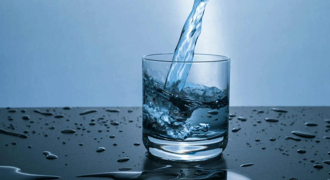 Water being poured into a glass with droplets on a dark surface, illustrating leak issues and fixes