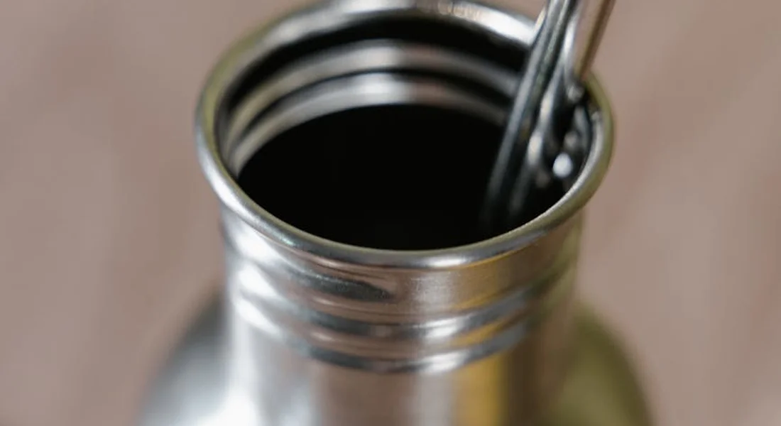 Close-up of a metal guinea pig water bottle with its opening exposed and a drinking tube visible, ready for cleaning.
