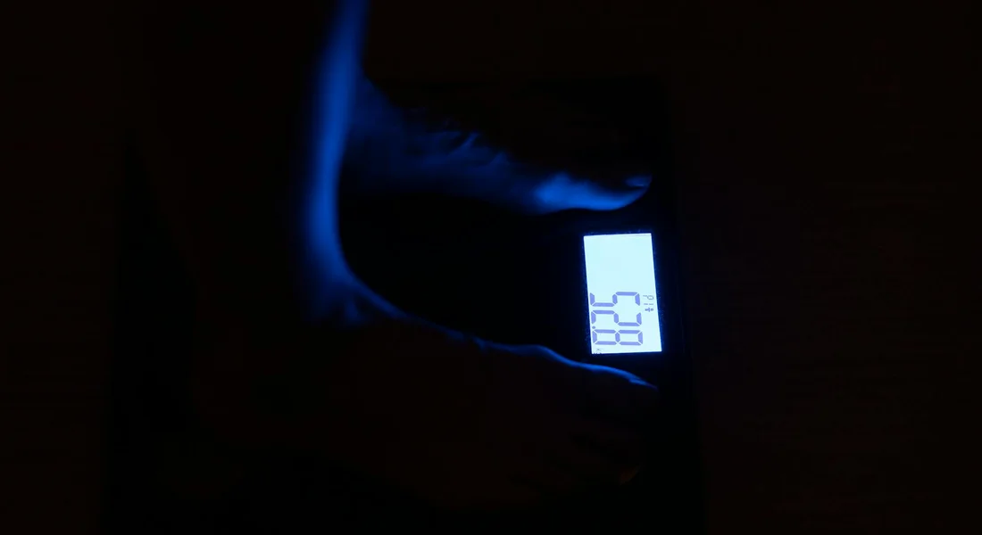 Dimly lit image of a digital scale with a guinea pig being weighed, showing a bright numeric display