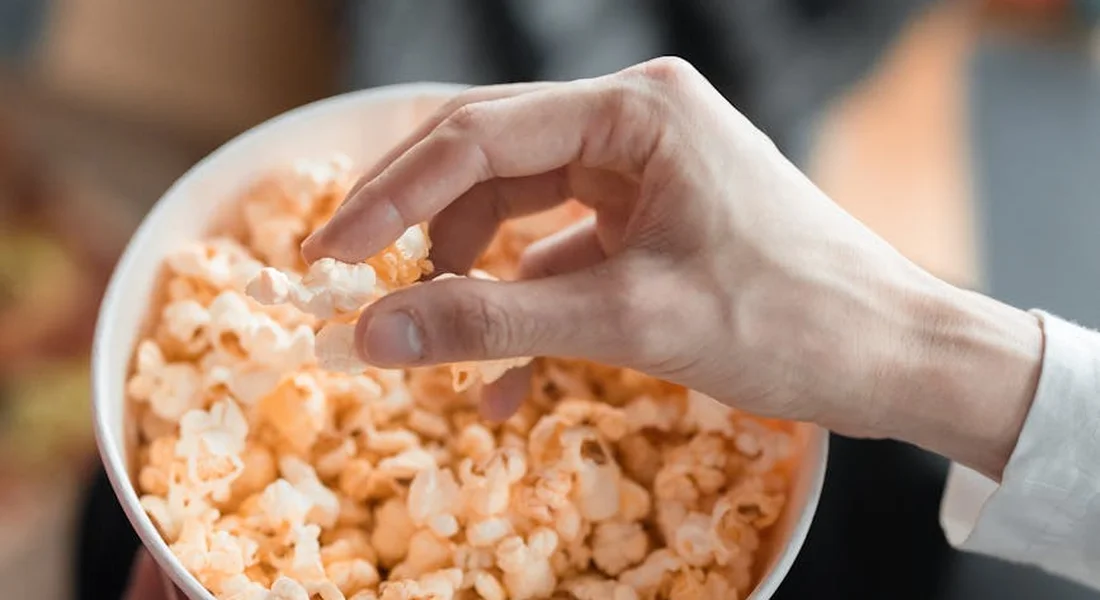 Close-up of a hand reaching into a bowl of popcorn