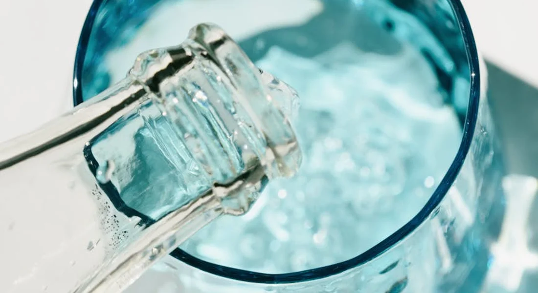 Close-up of a water bottle nozzle dispensing water into a container, illustrating bottle-style hydration for small pets