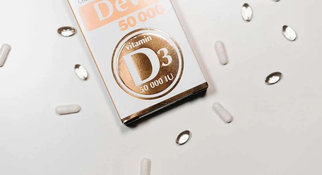 Close-up of a Vitamin D3 supplement box with scattered white capsules on a white surface, relating to calcium and phosphorus minerals in guinea pig nutrition.
