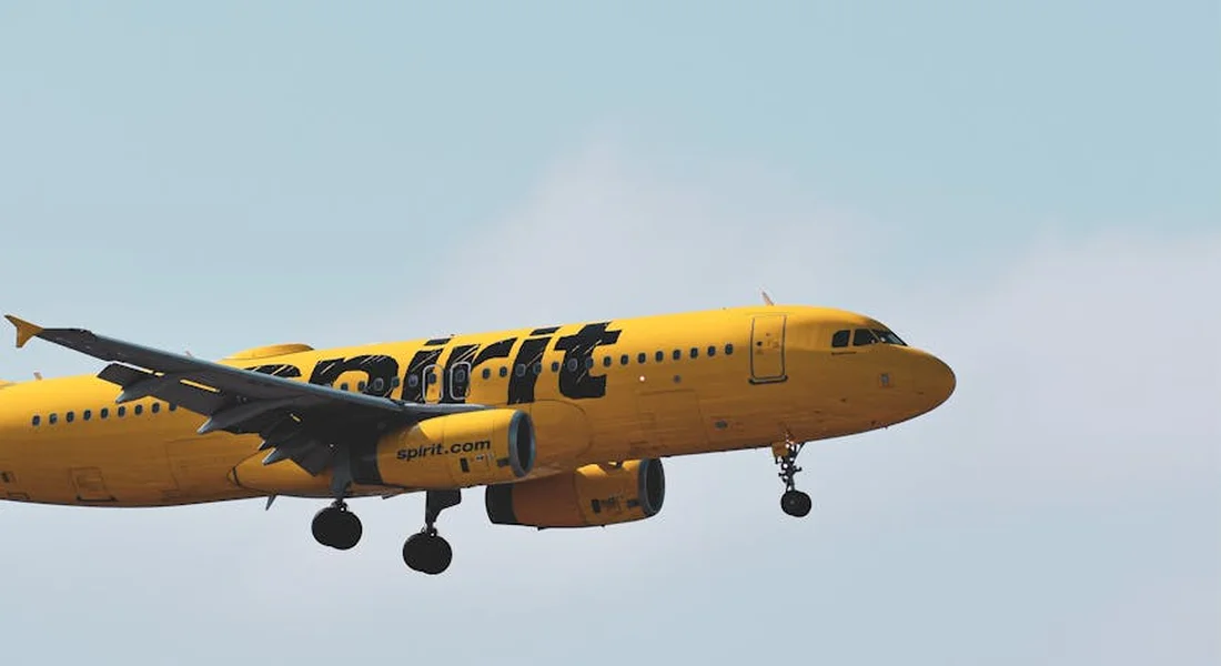 Yellow Jet2 passenger airplane with landing gear down, against a clear blue sky.