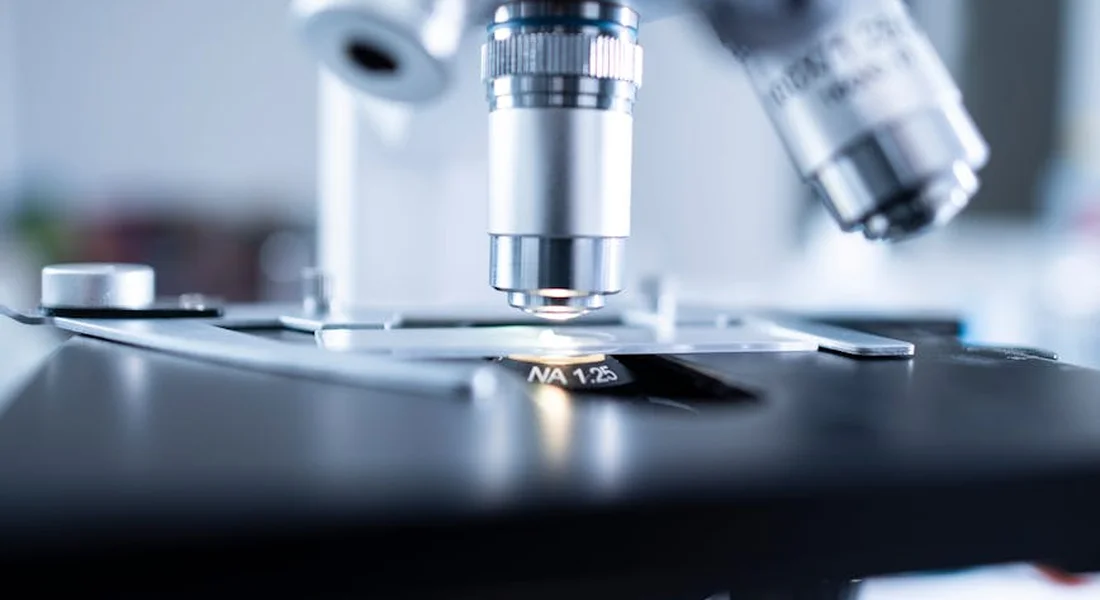 Close-up of a laboratory microscope with a slide, suggesting diagnostic scrutiny of samples.