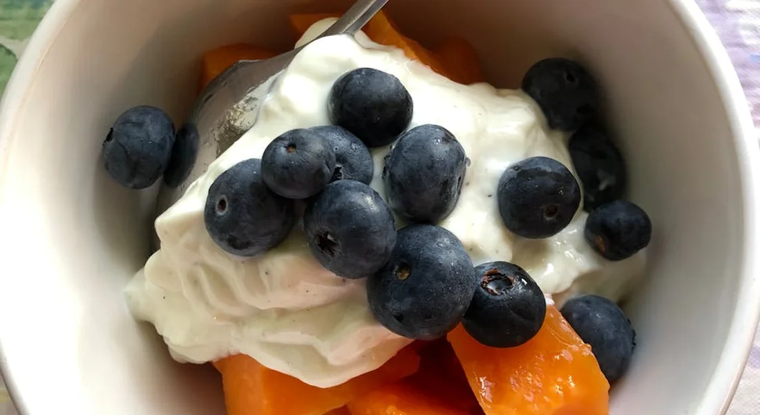 A bowl of yogurt with fresh blueberries and papaya chunks