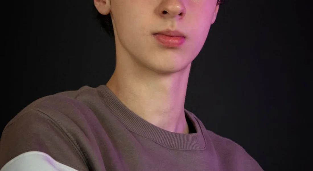 Portrait of a person wearing a brown sweater against a dark background, suggesting contemplation.