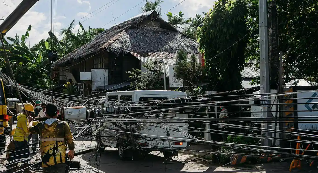 Street scene after a power outage showing a tangle of downed electrical wires, a parked vehicle, and pedestrians nearby.