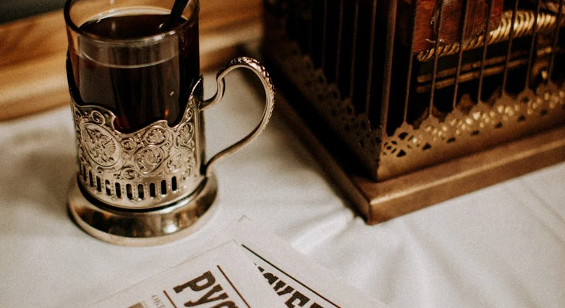 Close-up of a metal mug on a table beside a guinea pig cage, illustrating a home cleaning setup.