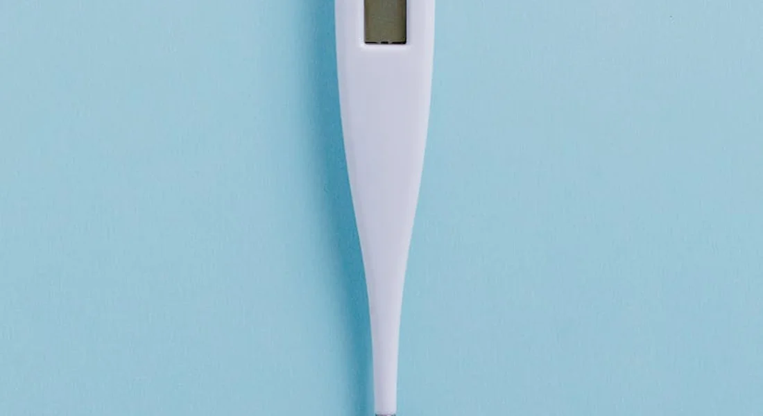 White digital thermometer against a light blue background