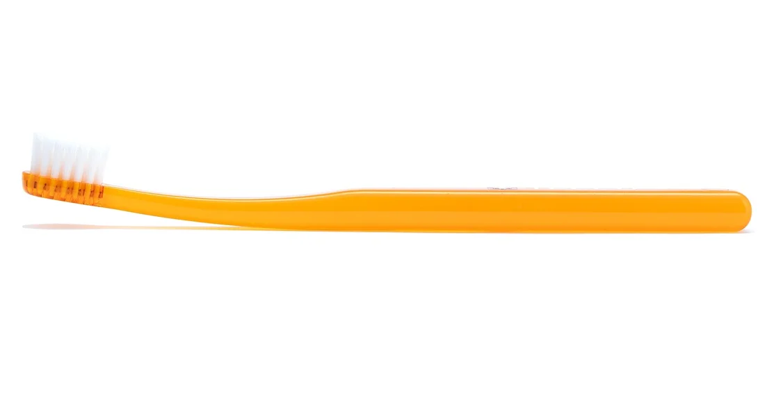 Orange toothbrush with white bristles on a white background