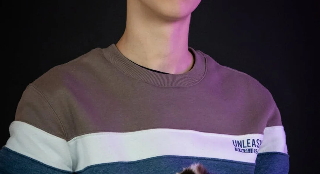 Close-up of a person wearing a brown and white striped sweater against a dark background.