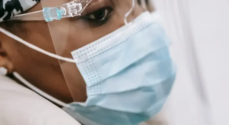 Close-up of a healthcare worker wearing a disposable surgical mask and protective eyewear