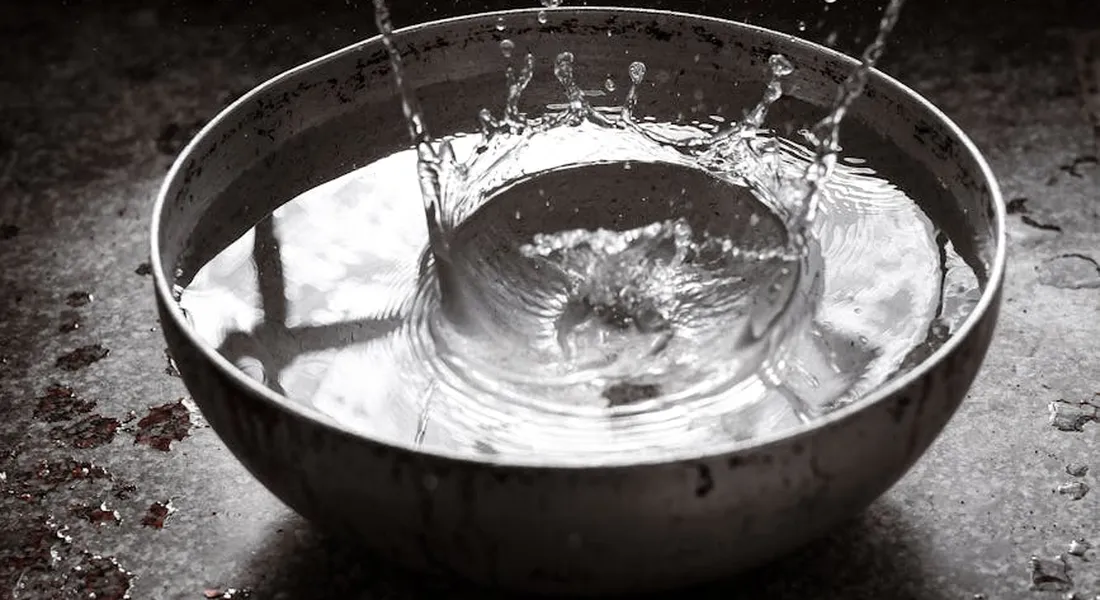 Metal water bowl with water splashing inside